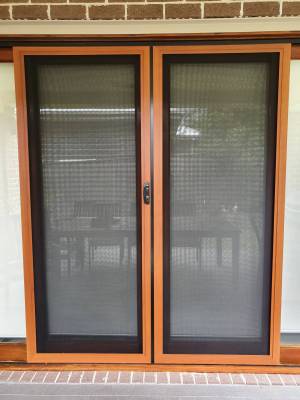 CB: 54 Double Sliding Security Doors Fitted With Stainless Steel Mesh In Cedar Wood Grain Finish & Black Trimmings.