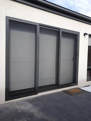 CB: 57 Angle View Stacker Sliding Security Doors Fitted With Stainless Steel Mesh. Displaying The Two Security Doors In A Closed Position & The Third Security Fixed Panel Fitted With Tamper Proof Screws In Monument.