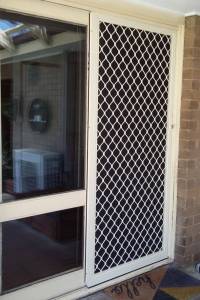 Protect Your Home: The Importance of Security Screen Doors in Melbourne 4 CB: 45 Standand Diamond Grille in Primrose With Black Privacy Mesh Installed on The Outside Track